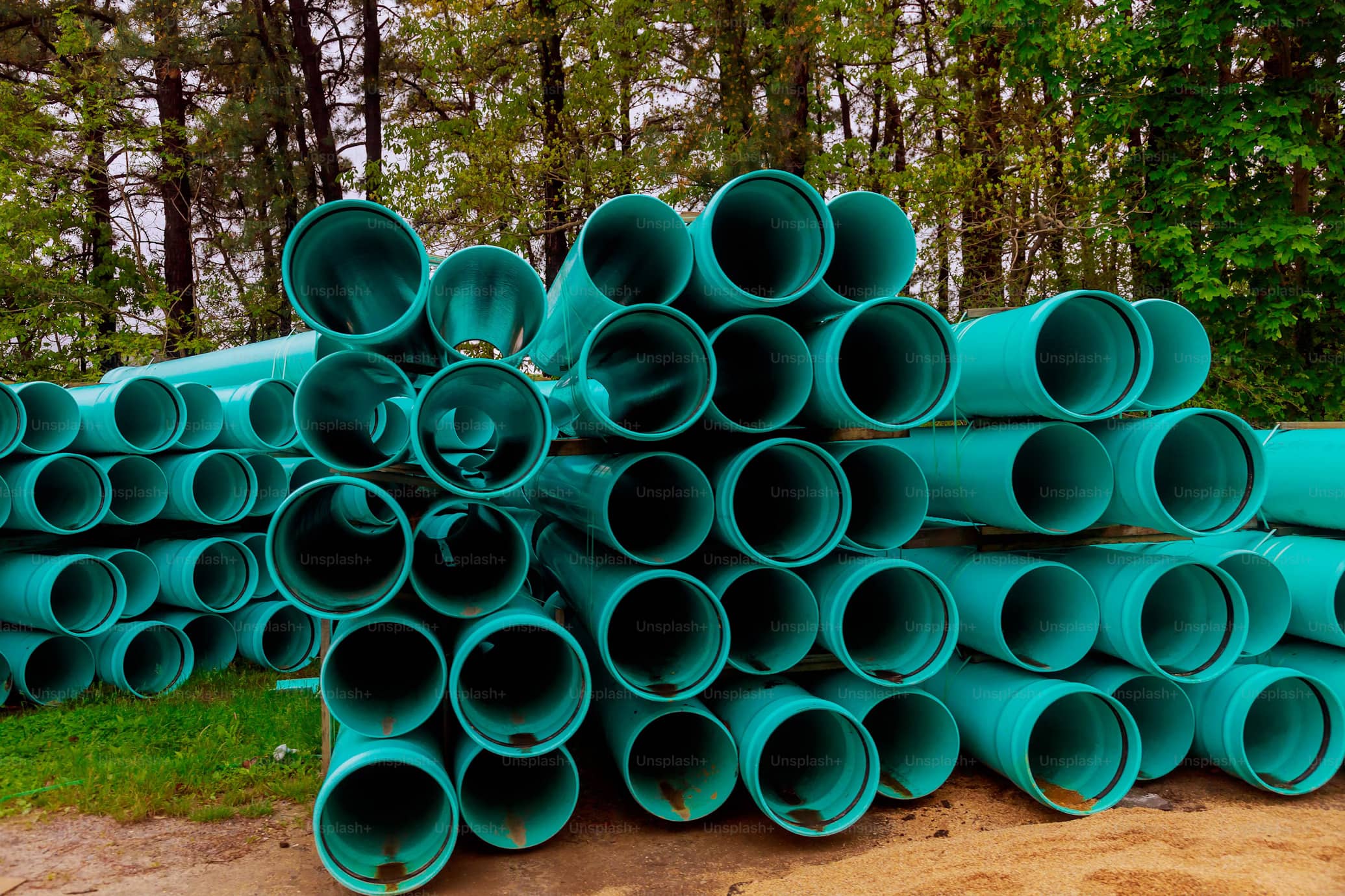 A big pile of large green industrial PVC pipes